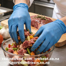 Person preparing a salad with blue gloves in a kitchen setting