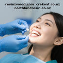Person receiving dental treatment with gloved hands applying a substance to their teeth, with website URLs displayed.