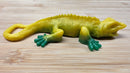 Yellow and green toy lizard on a wooden surface
