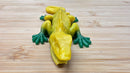 Yellow and green frog-shaped object on a wooden surface