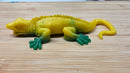 Yellow and green toy lizard on a wooden surface