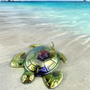 Decorative turtle on a sandy beach with clear water in the background