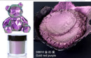 Purple cosmetic product with a bear-shaped container and powder on a black background.